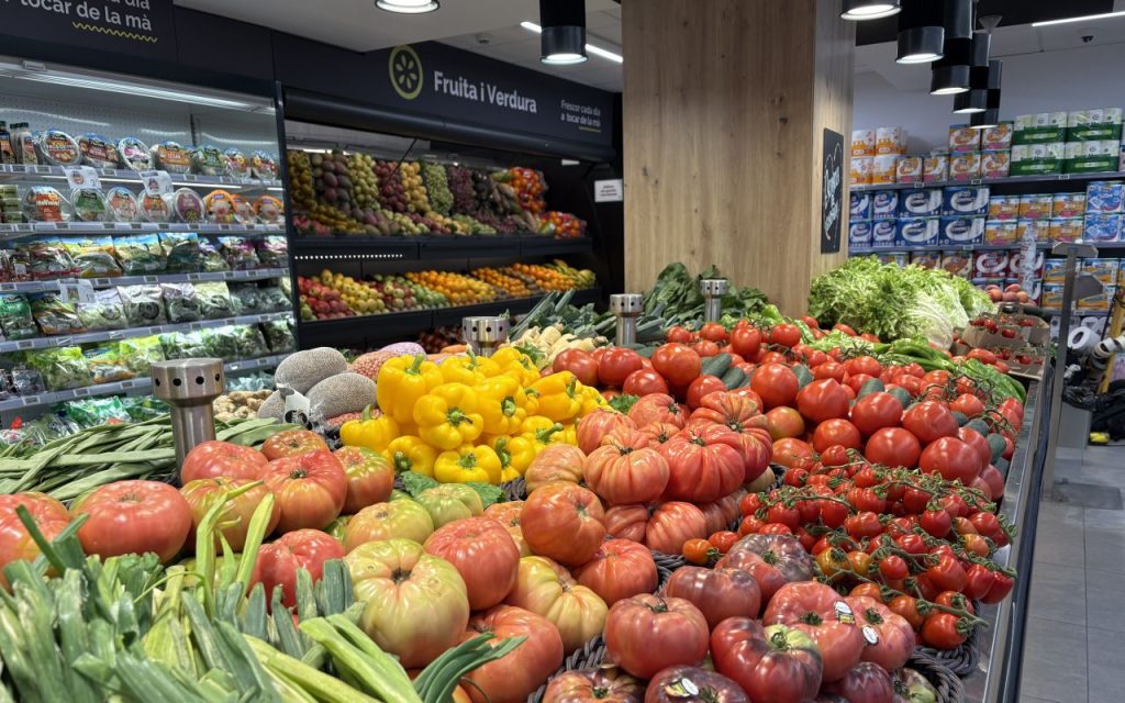 Sección de frutas y hortalizas de un supermercado Condis, con tomates y pimientos en primer plano.